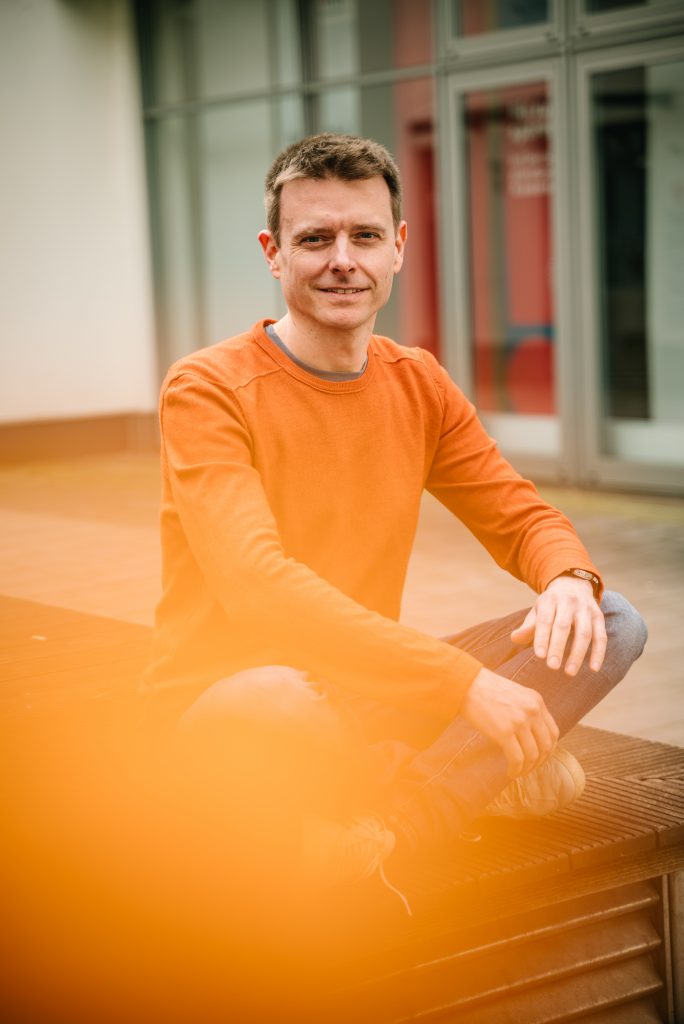 Robert Mayer vor einem Gebäude sitzend.
