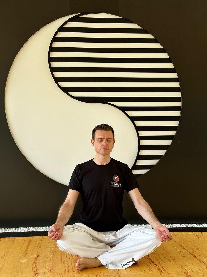 Breathwork-Trainer Robert Mayer meditierend vor einem Yin-Yang-Symbol