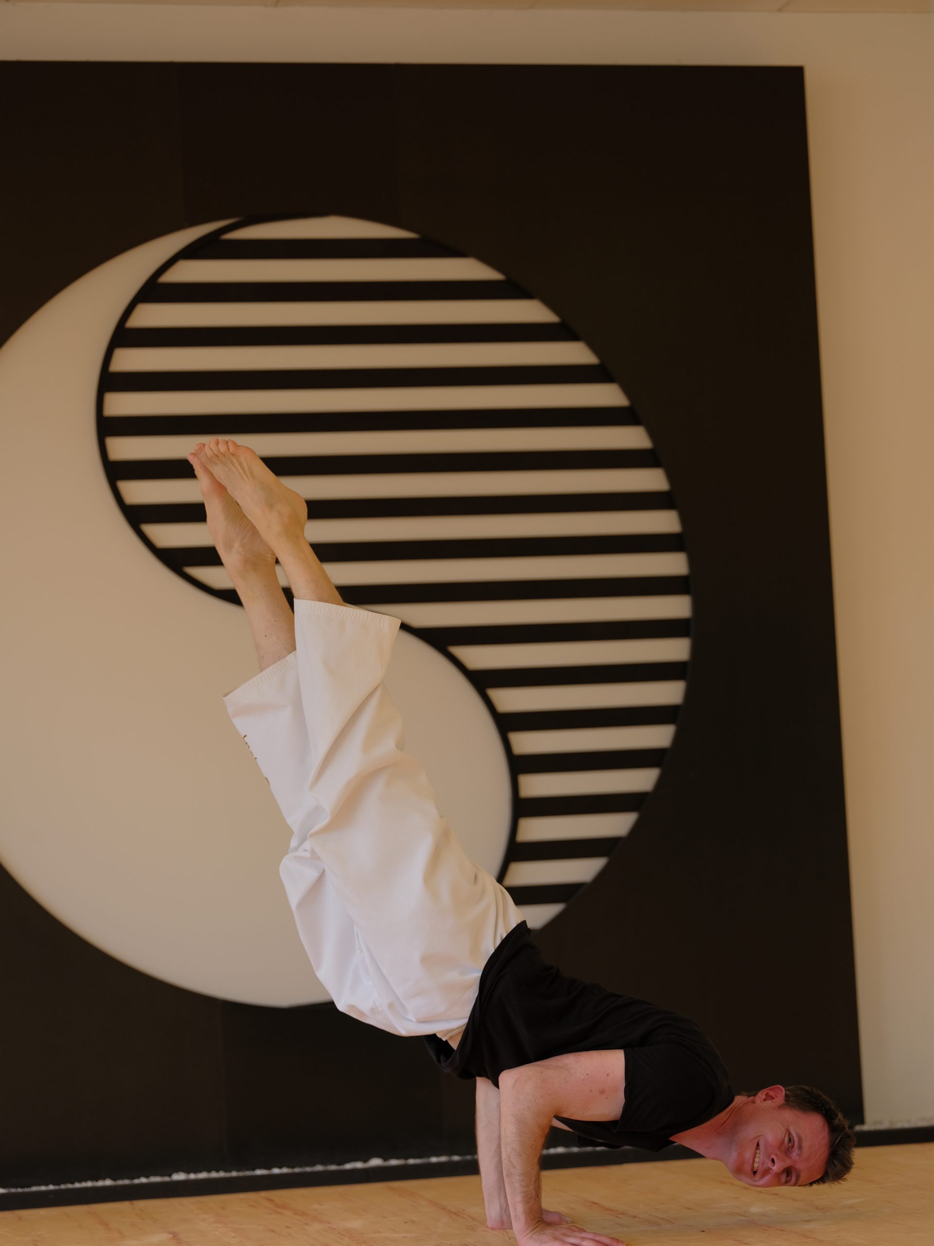 Pilates-Trainer und Taekwondo-Lehrer Robert Mayer in diagonalem, gebeugtem Handstand